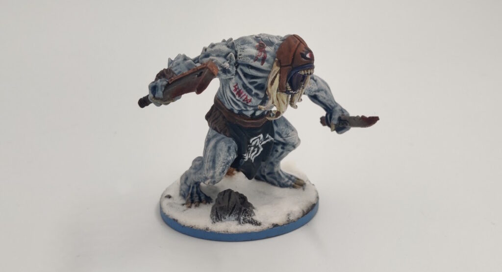 Mantic "Butcher": the skin is pale, blueish white,  both arms are normal, the loincloth sports the raven banner, it has a blonde bear, and the headcover is leather with an red eye painted on it. The knife and the axe have died blood effects. 