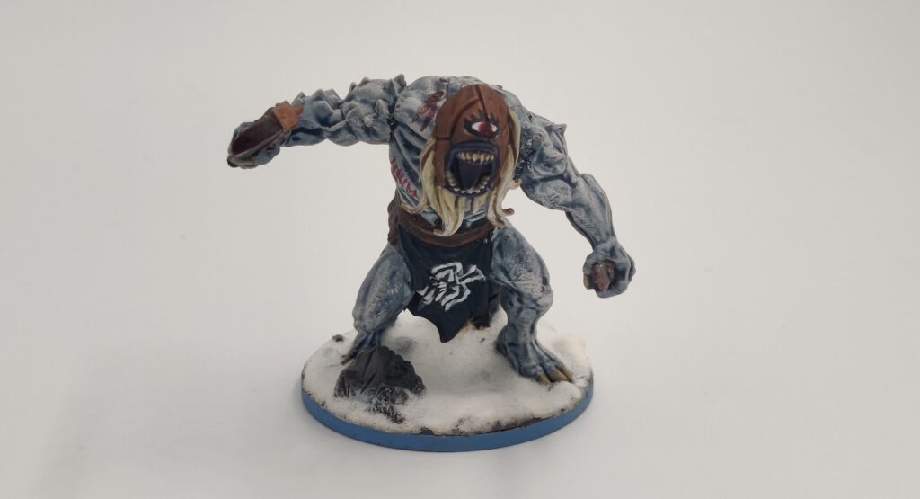 Mantic "Butcher": the skin is pale, blueish white,  both arms are normal, the loincloth sports the raven banner, it has a blonde bear, and the headcover is leather with an red eye painted on it. 